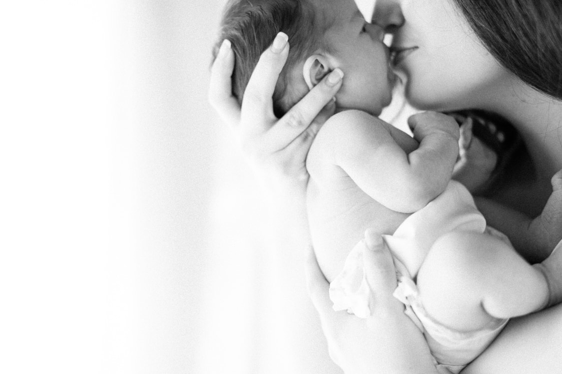 savannah newborn photographer. black and white photograph of mom kissing newborn
