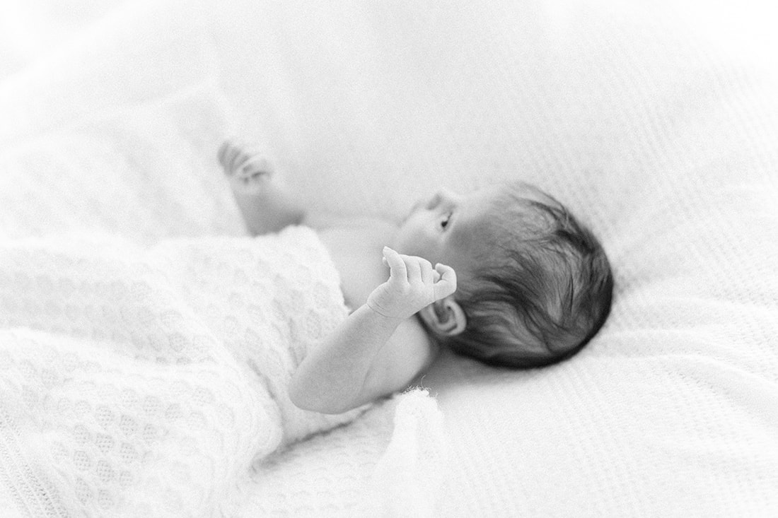 savannah newborn photographers. black and white image of newborn boy with hand up
